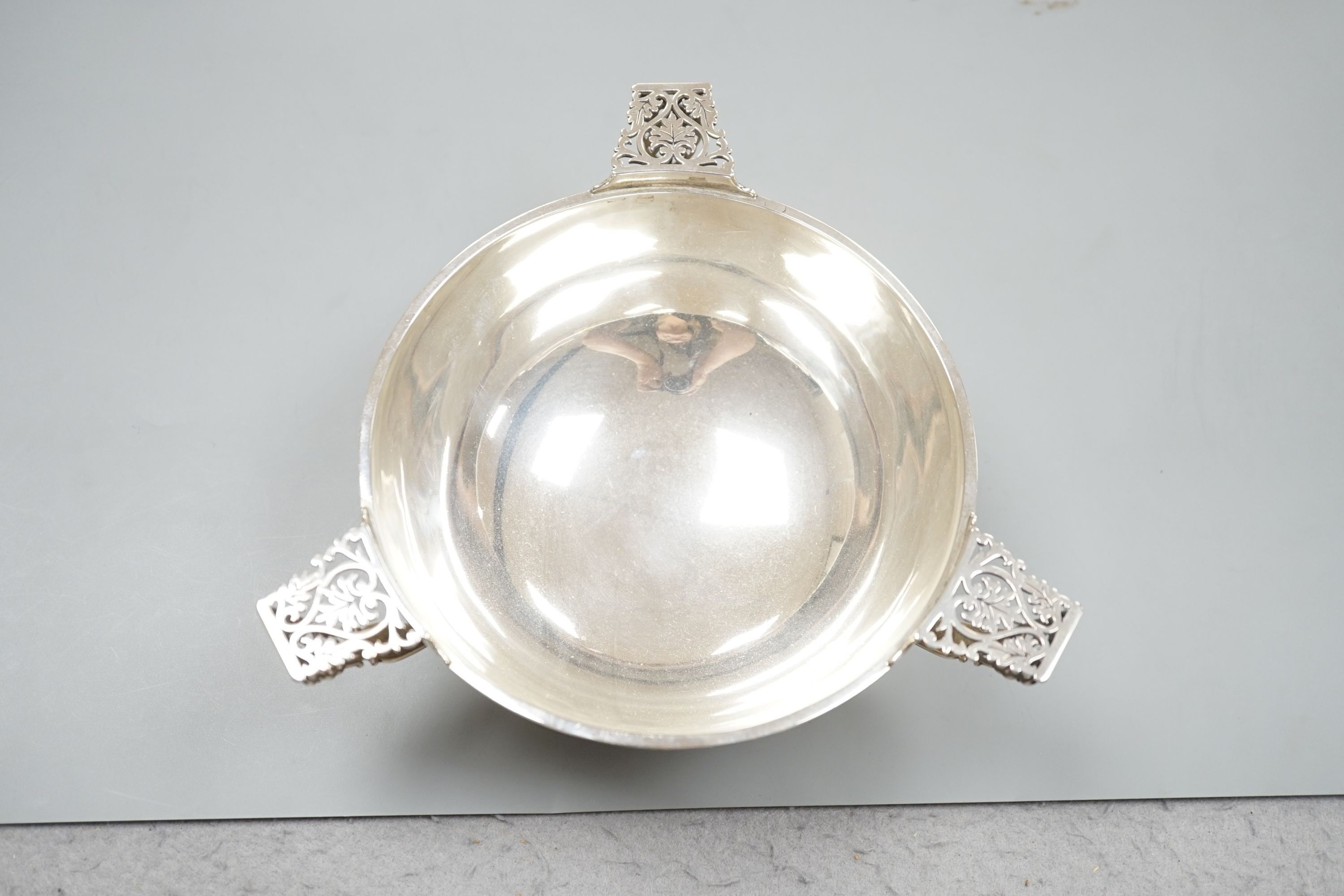 An Edwardian silver circular bowl, with three piece harp shape handles, Goldsmiths & Silversmiths Co Ltd, London 1906, on pedestal foot, diameter 16.25cm, 14oz.